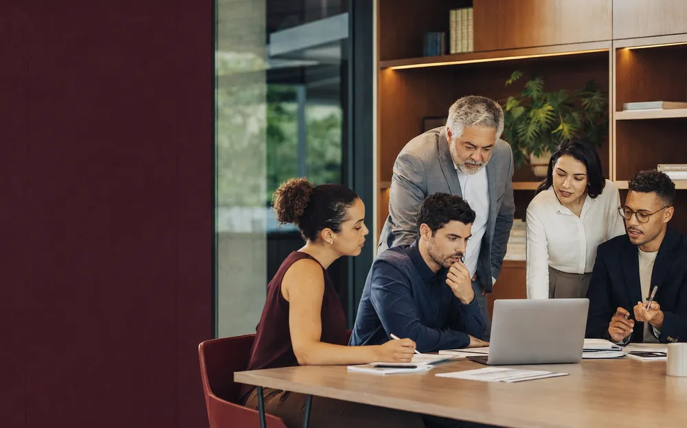 Equipe reunida em torno de um notebook, analisando números